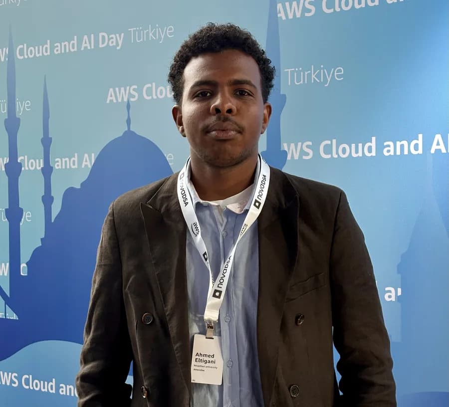 Ahmed Eltigani wearing an attendee badge in front of the AWS Cloud and AI Day Türkiye backdrop